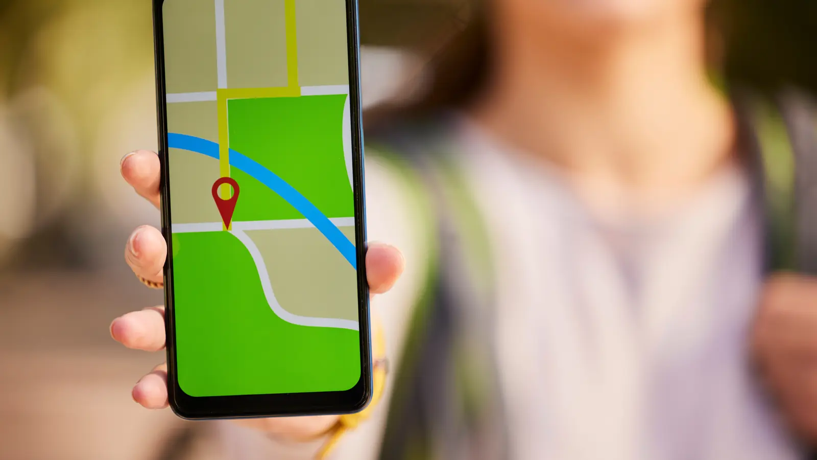 Frau hält Smartphone mit Karten-App und rotem Standort-Pin in die Kamera — Symbol für Google Business Profile Optimierung im deutschen Mittelstand
