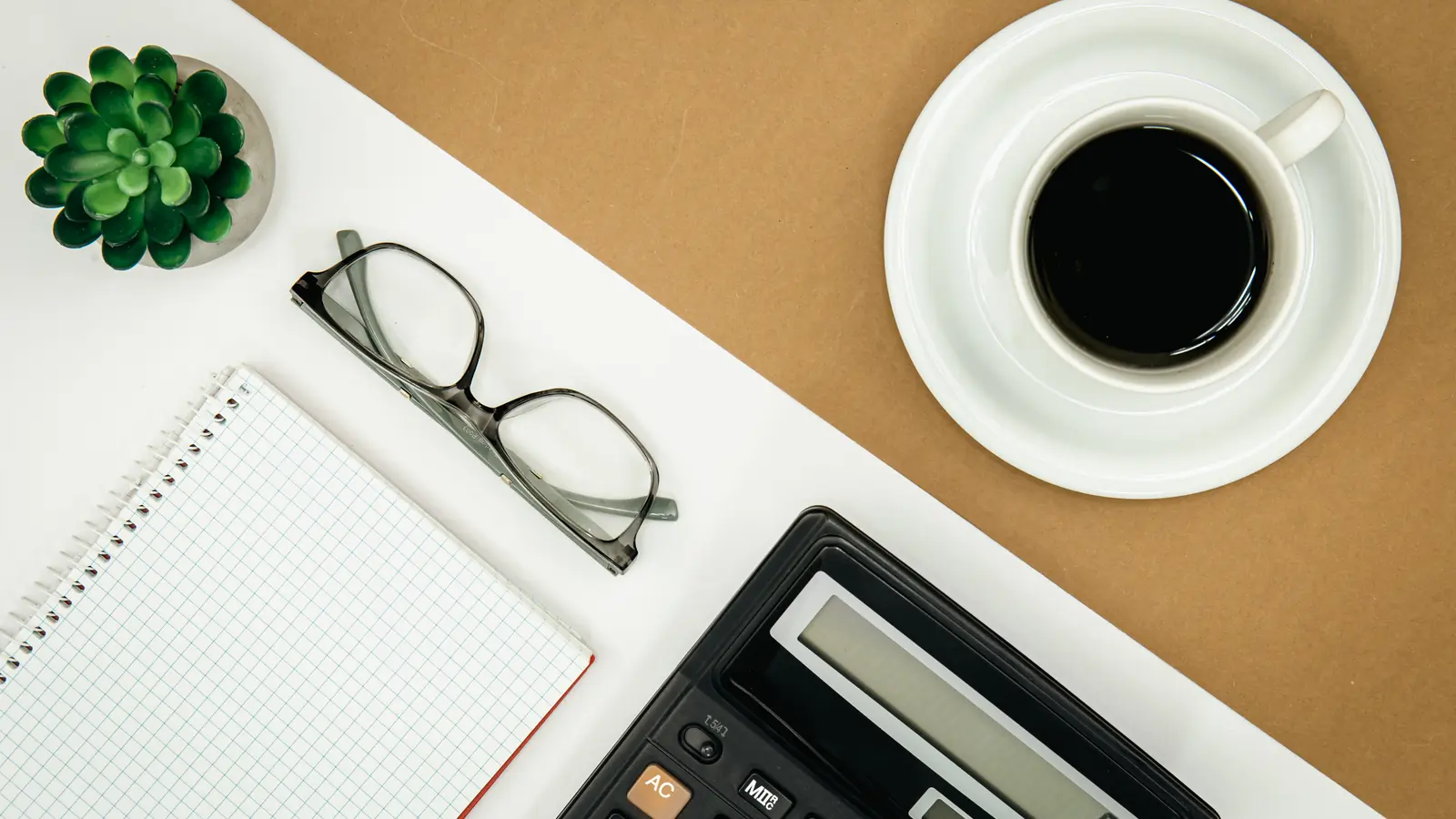 Flat-Lay-Aufnahme von Notizblock, Taschenrechner und Kaffeetasse auf Schreibtisch — Symbol für ehrliche SEO-Kostenkalkulation für Mittelständler in Deutschland
