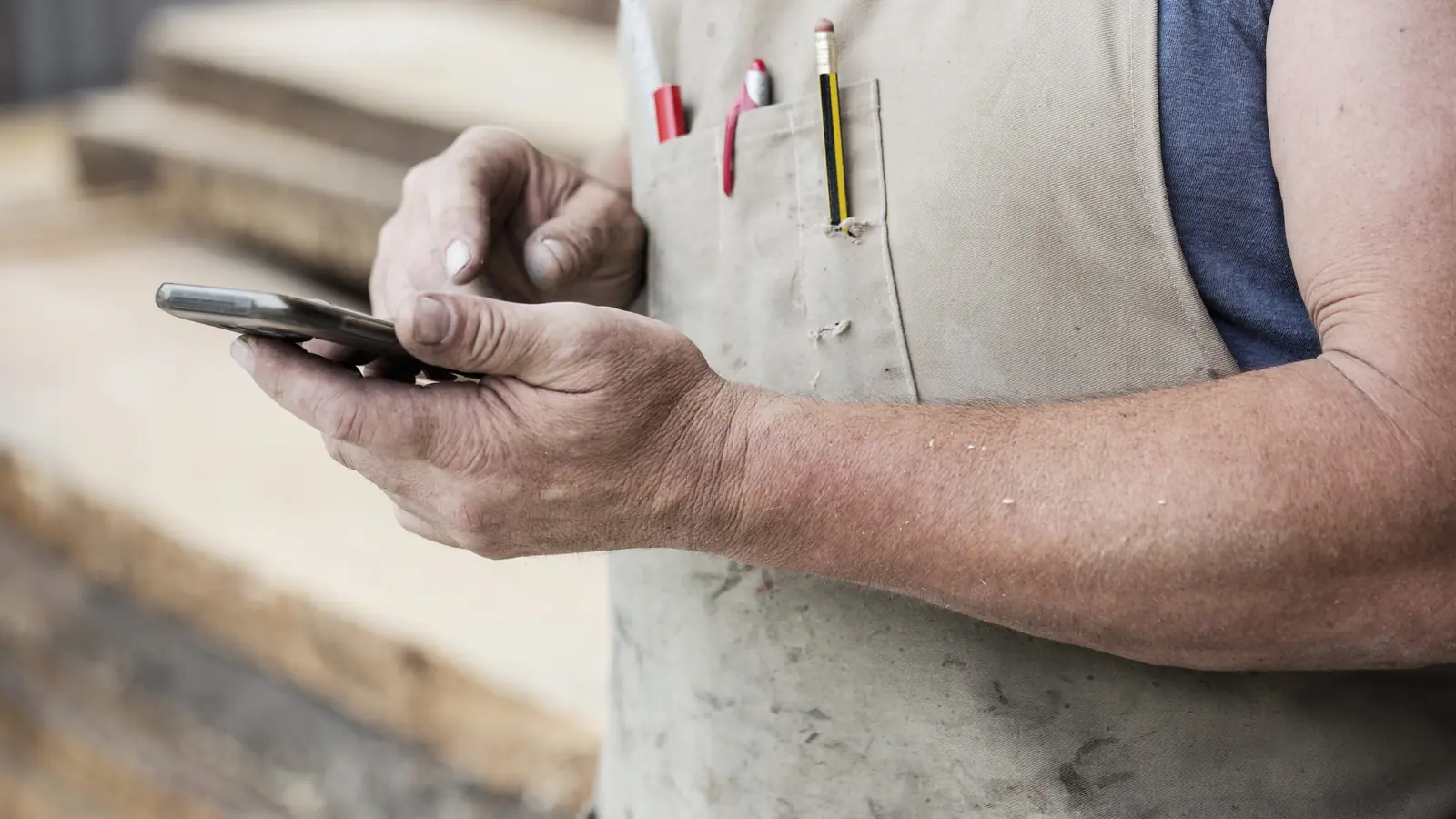Handwerker auf der Baustelle nutzt Smartphone — sinnbildlich dafür, dass die meisten Handwerker-Anfragen 2026 mobil über Google und die eigene Website kommen