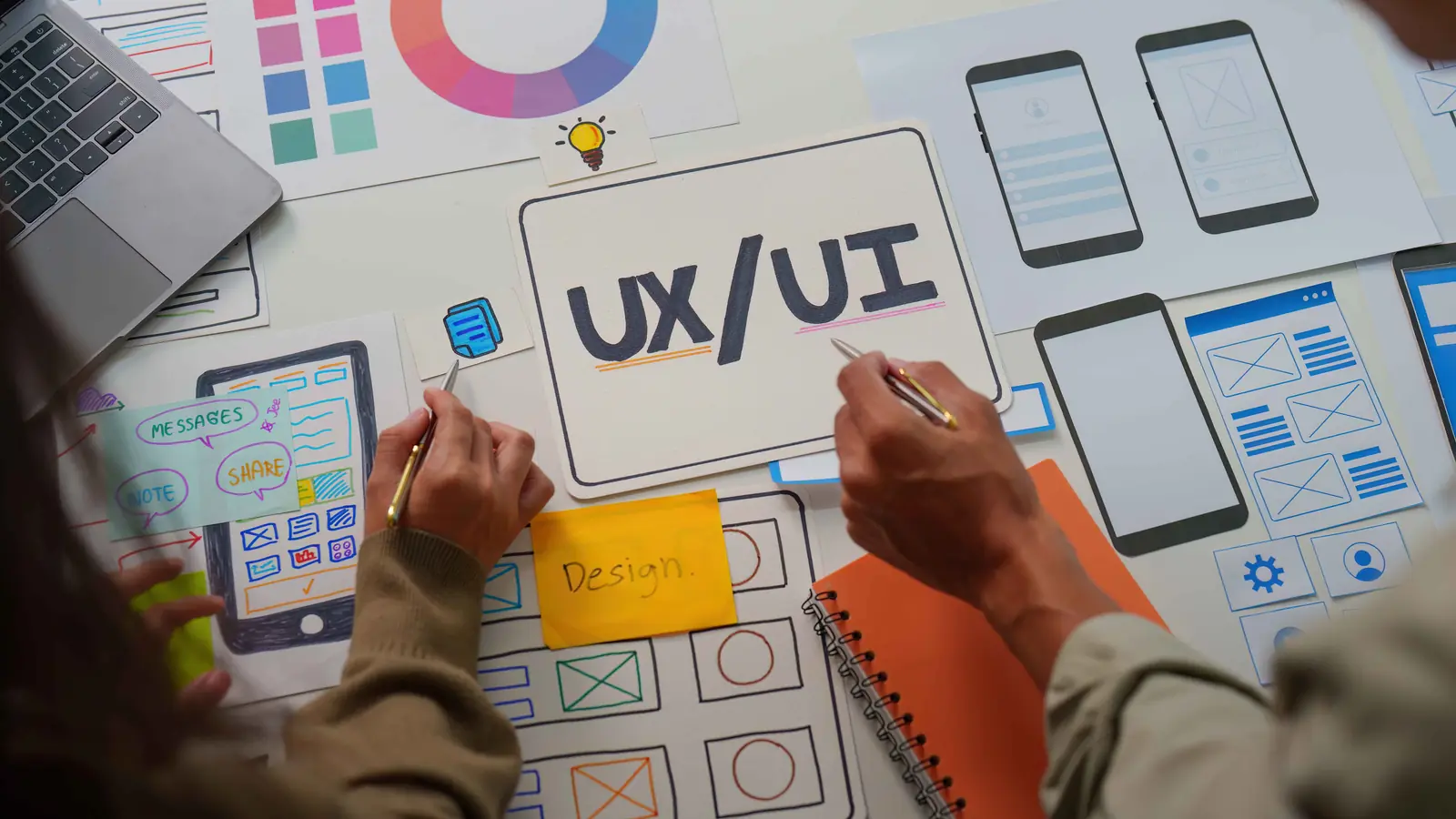 UX/UI Designer-Team beim Sketchen von App-Wireframes auf Papier — Symbol für aktuelle Webdesign-Trends 2026 für Mittelständler