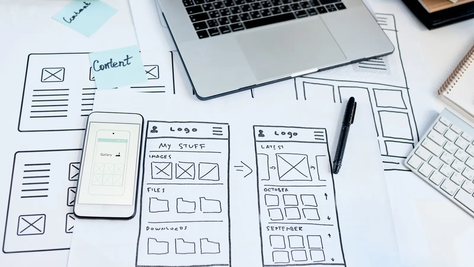 Designer-Arbeitsplatz mit Laptop, Smartphone und App-Skizzen — sinnbildlich für die strukturierte Planung eines Website-Relaunches mit klarer Konzeption und SEO-Sicherung